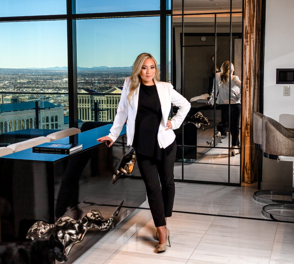 Amanda Wang standing in upscale room with large windows wearing a white jacket